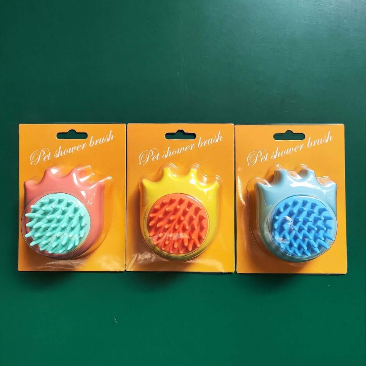 Three cat paw-shaped pet bath brushes in orange, yellow, and blue for dog and cat massage.